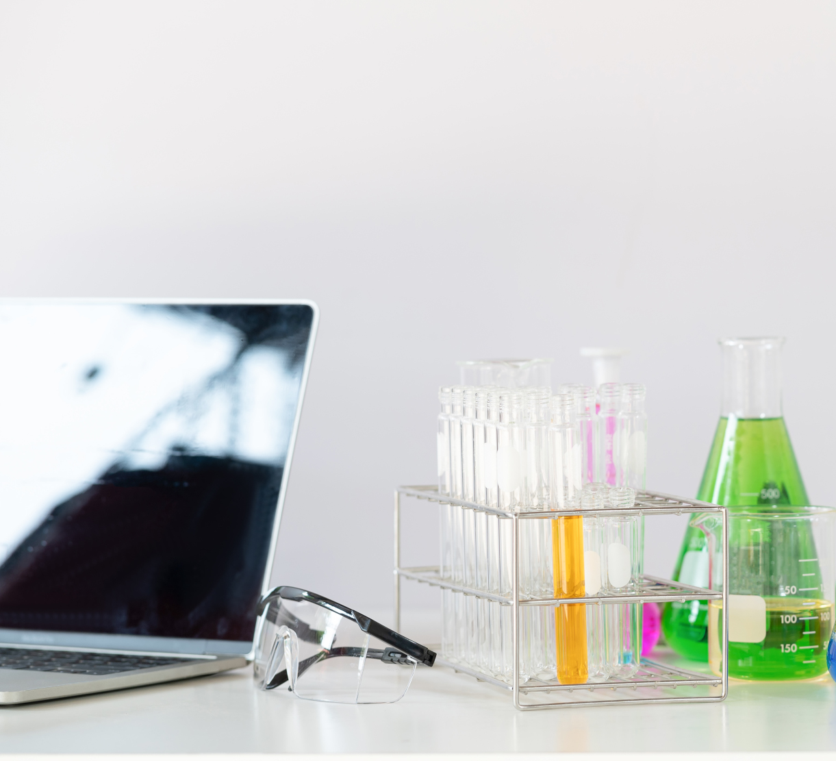 Portátil, gafas y equipo científico de cristal con líquido de colores